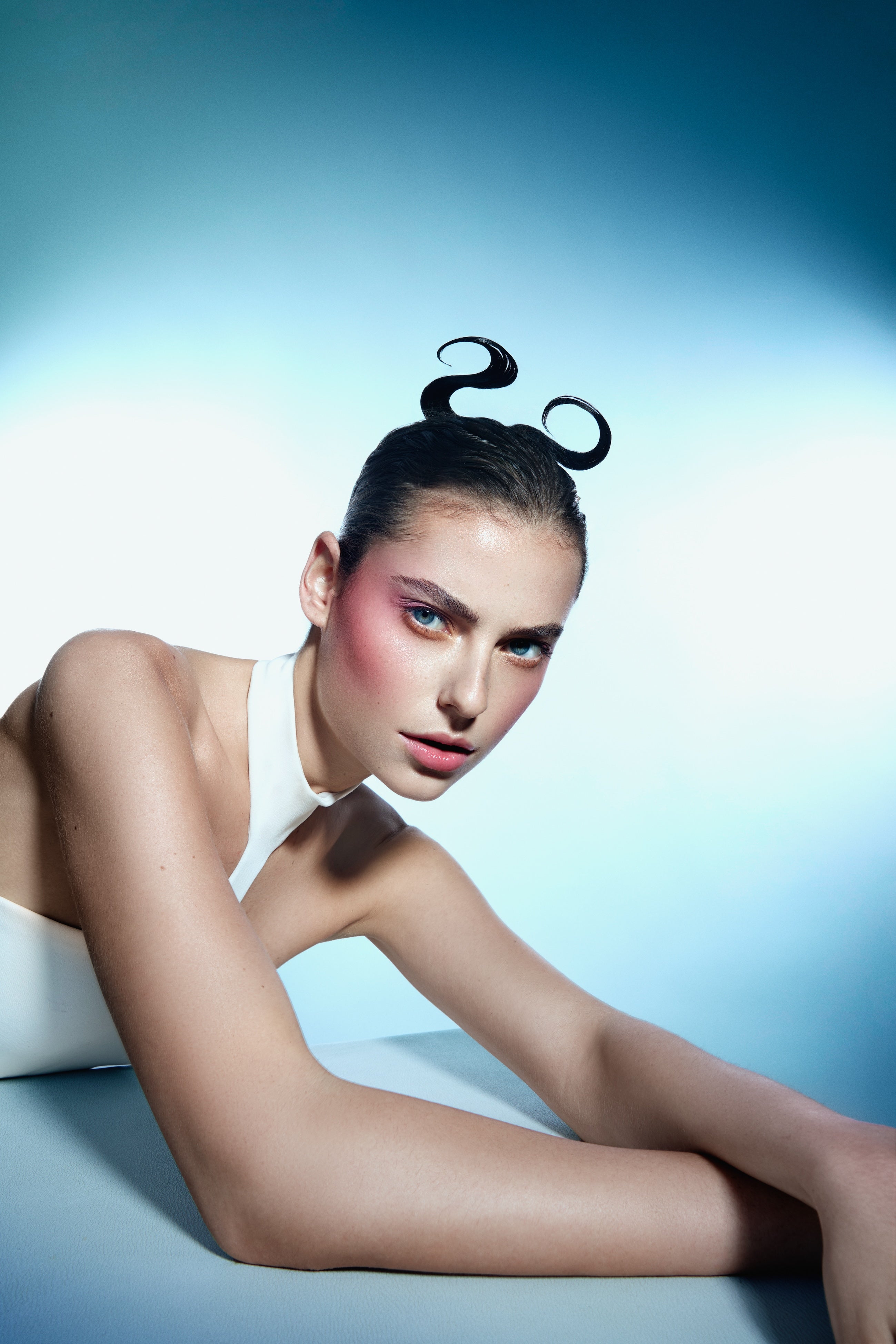 Model mit außergewöhnlicher Frisur vor blauem Hintergrund